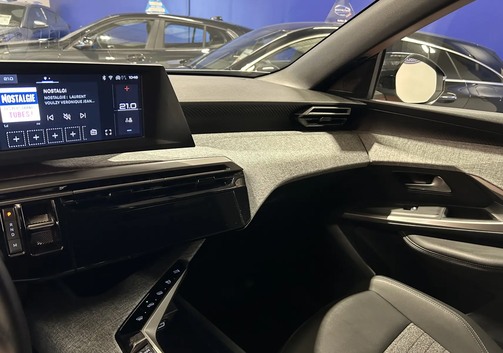 Vue intérieure côté passager du Peugeot 5008 gris Artense, mettant en valeur la planche de bord moderne et l'écran tactile central.