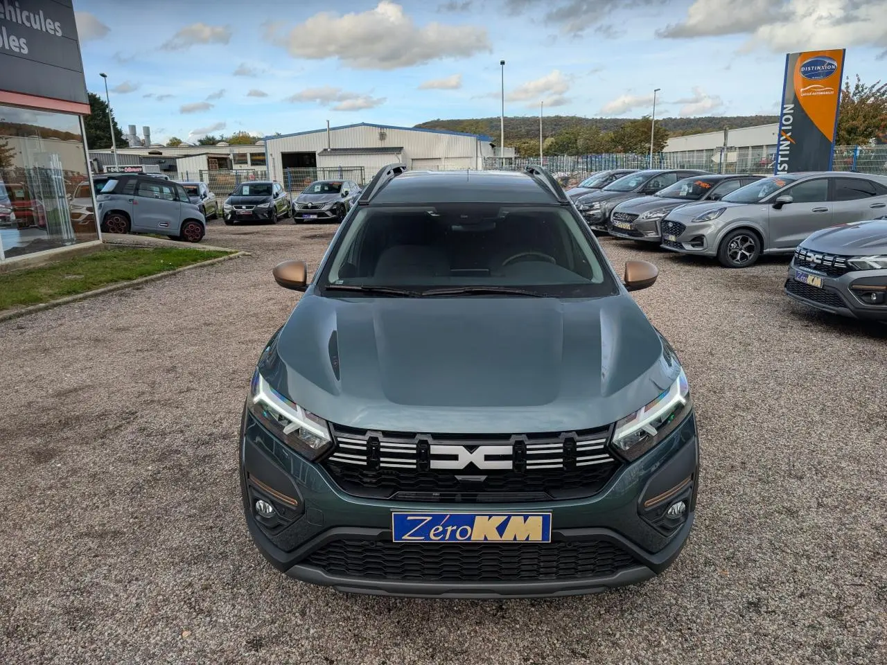 Vue avant d'un Dacia Jogger 2025 vert métallisé avec calandre noire et barres de toit visibles.