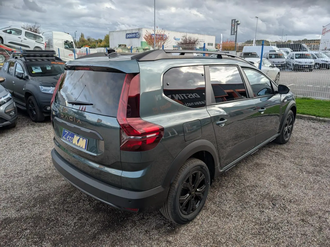 Vue 3/4 arrière droite d'un Dacia Jogger vert métallisé avec jantes noires et vitres teintées stationné en extérieur.