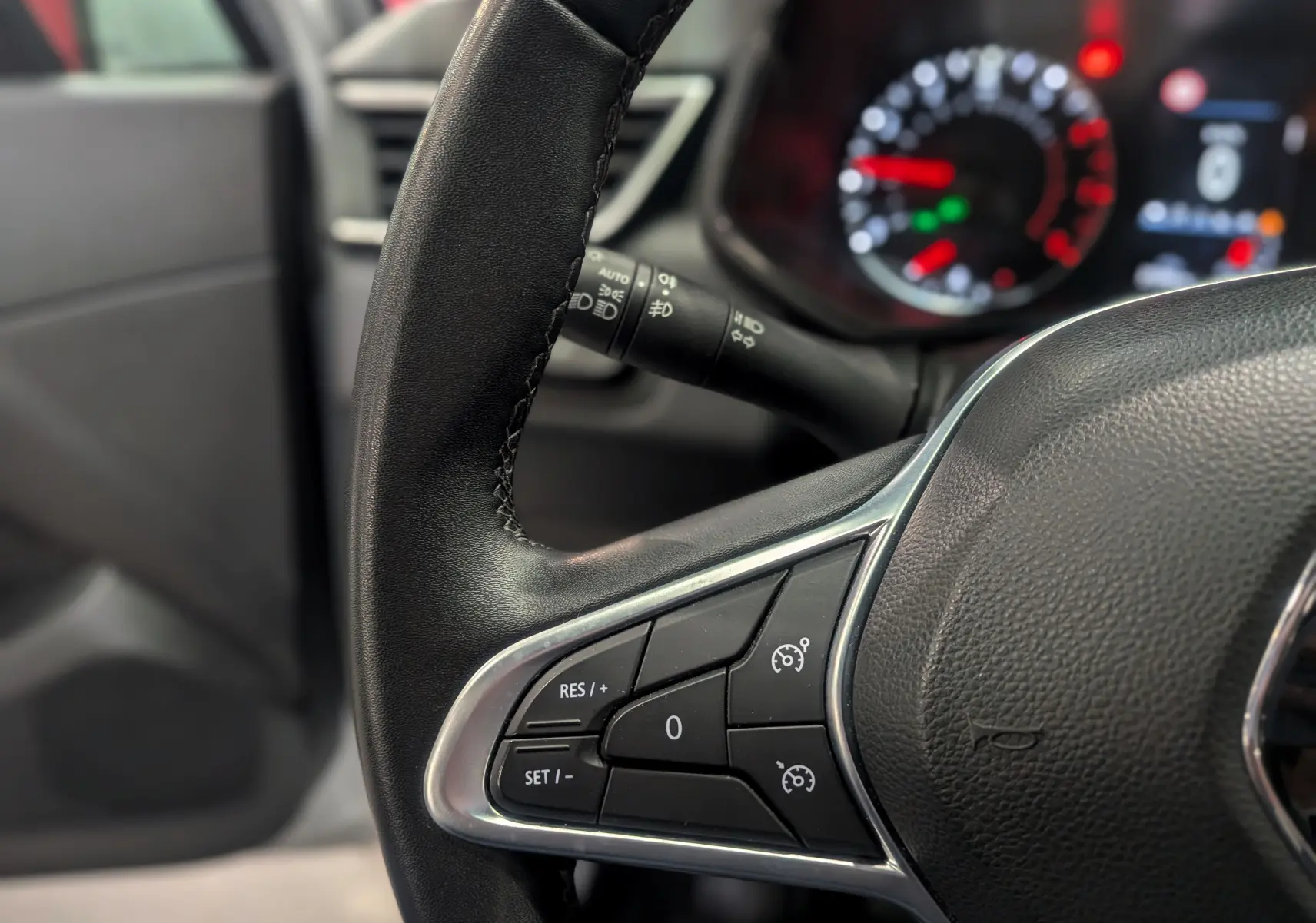 Gros plan sur le volant noir de la Renault Clio V TCe 90, montrant les commandes de régulateur de vitesse côté gauche.