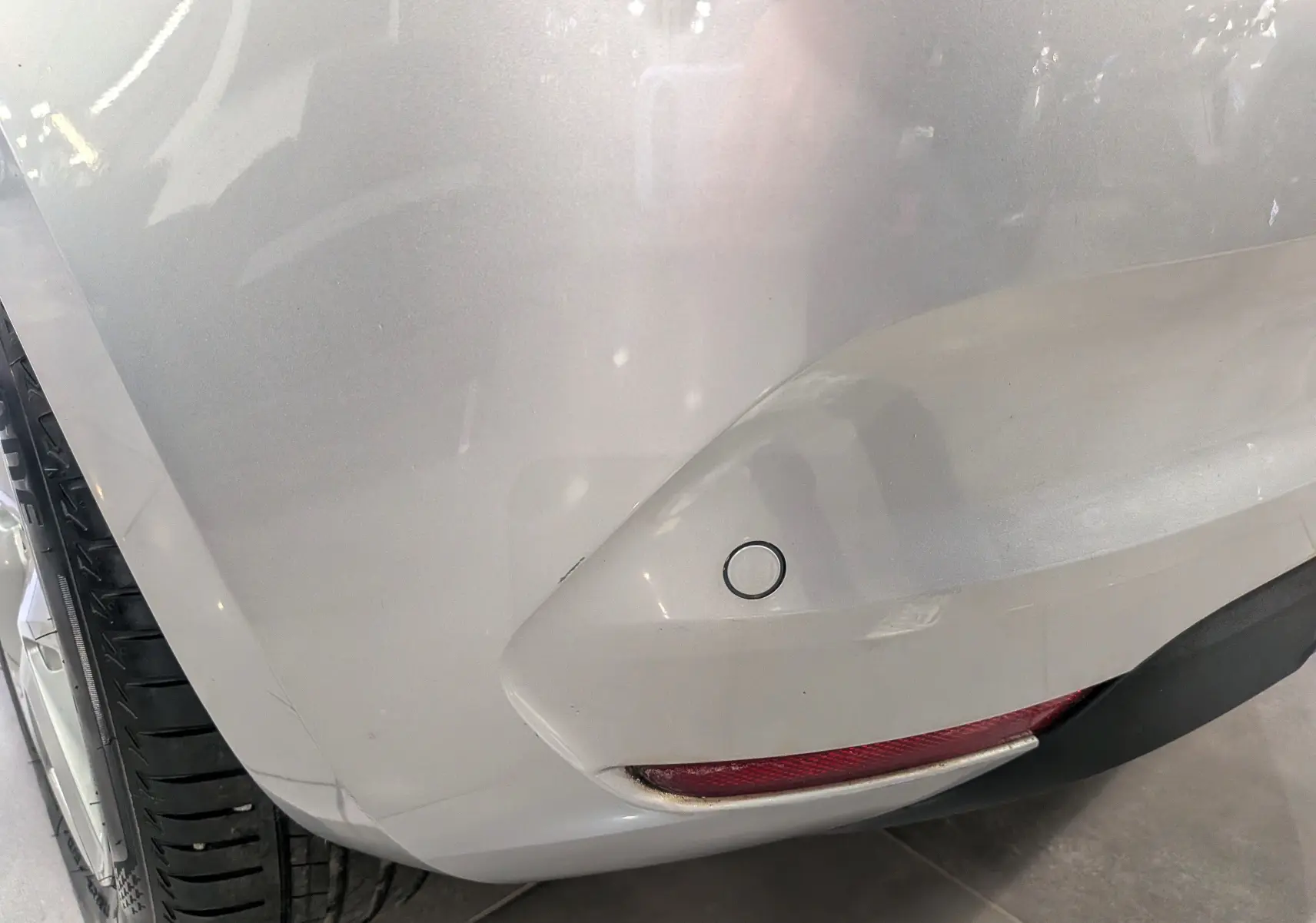 Gros plan sur l'angle arrière droit gris platine d'une Renault Clio V TCe 90 CH AUTO-ECOLE avec feu antibrouillard et capteur de recul.