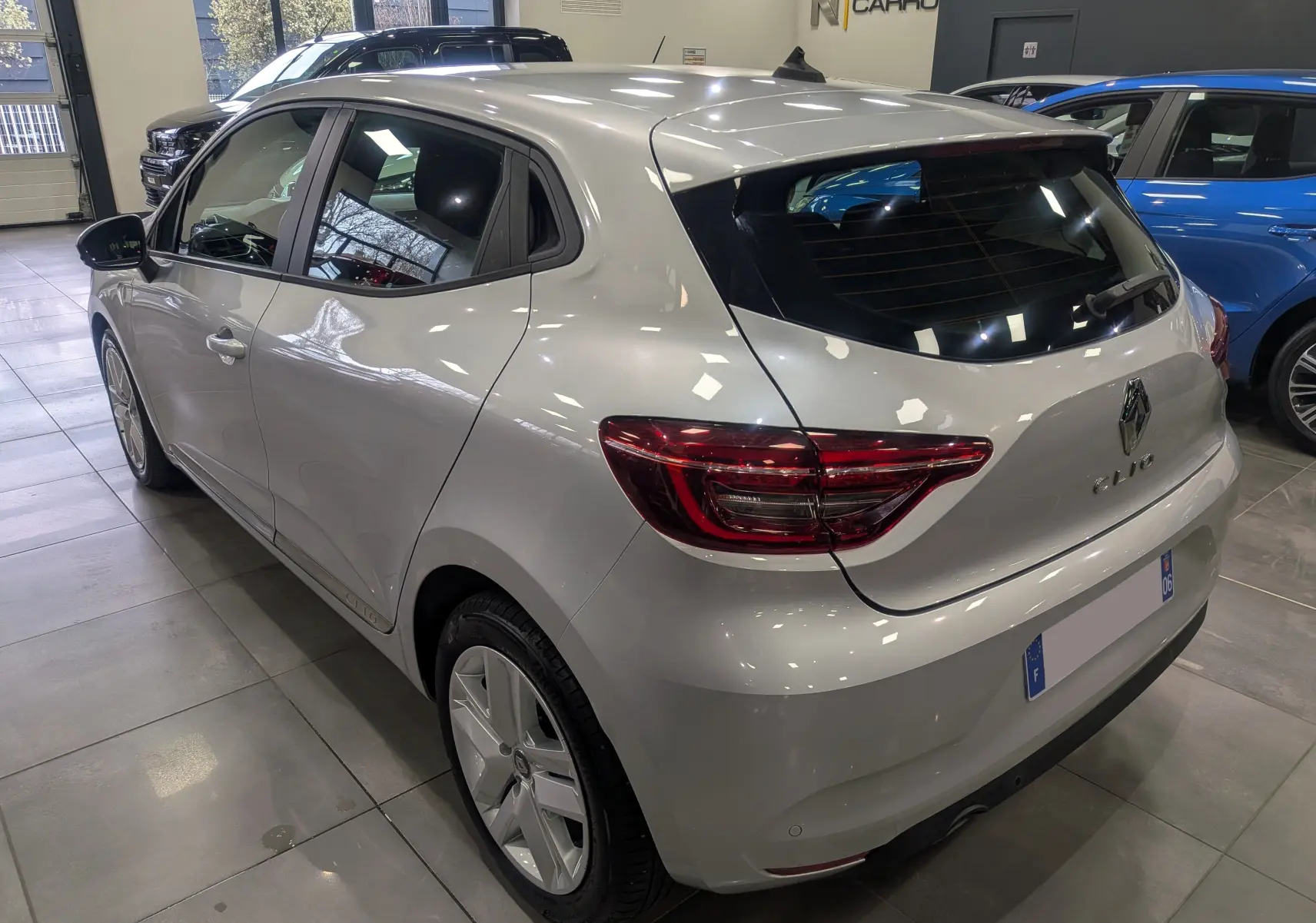 Vue 3/4 arrière droite d'une Renault Clio V gris platine en intérieur, avec feux arrière LED et jantes alliage.