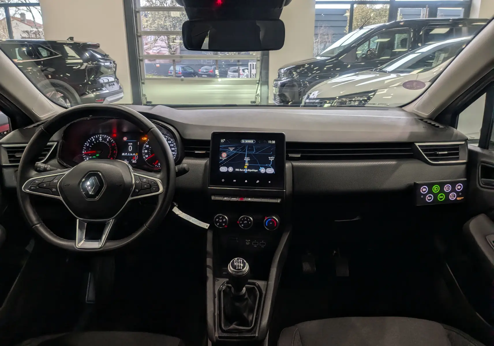 Vue intérieure avant de la Renault Clio V TCe 90 Auto-école 2021, tableau de bord noir avec écran tactile et levier de vitesses manuel.