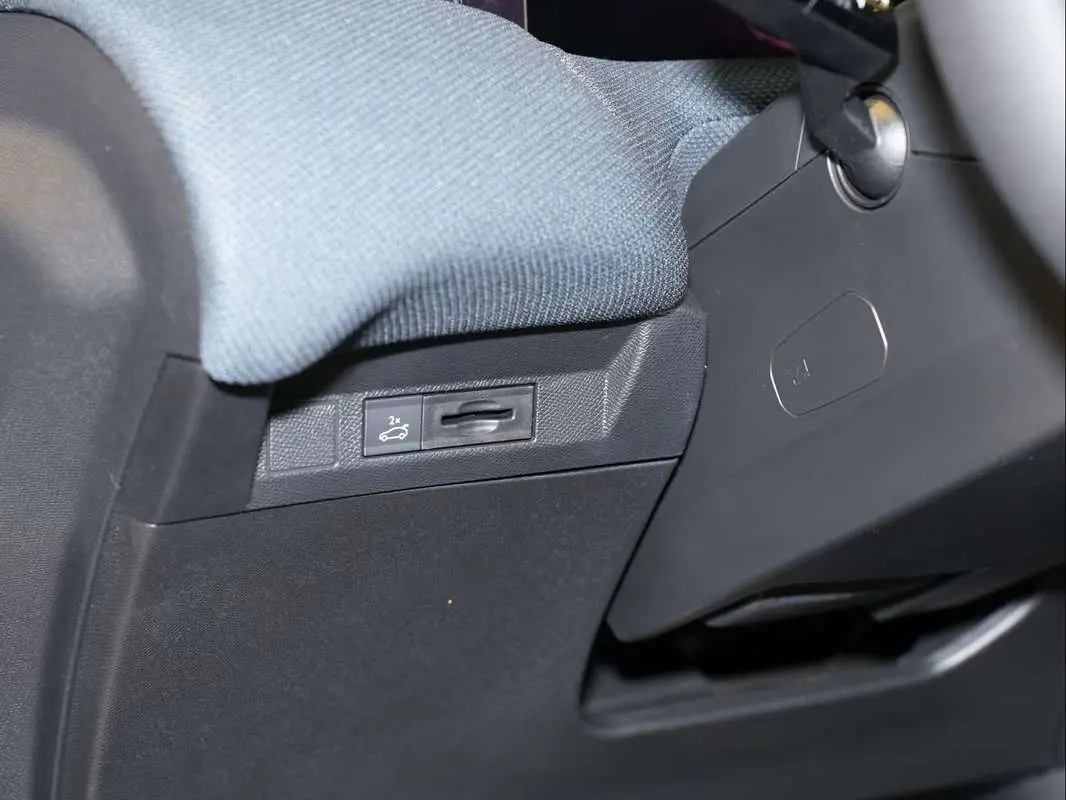 Détail intérieur côté gauche montrant le bouton d'ouverture du hayon sur le tableau de bord noir du Citroën C5 Aircross 2026.