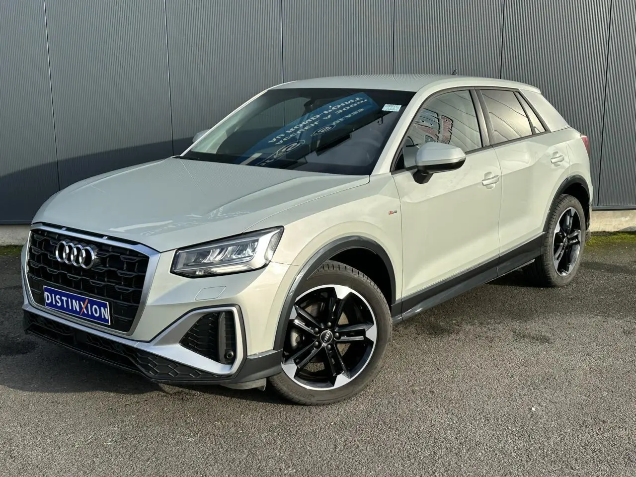 Audi Q2 30 TFSI S-Line 2024 argent rosé, vue 3/4 avant droit, jantes alliage noir poli et vitres surteintées.