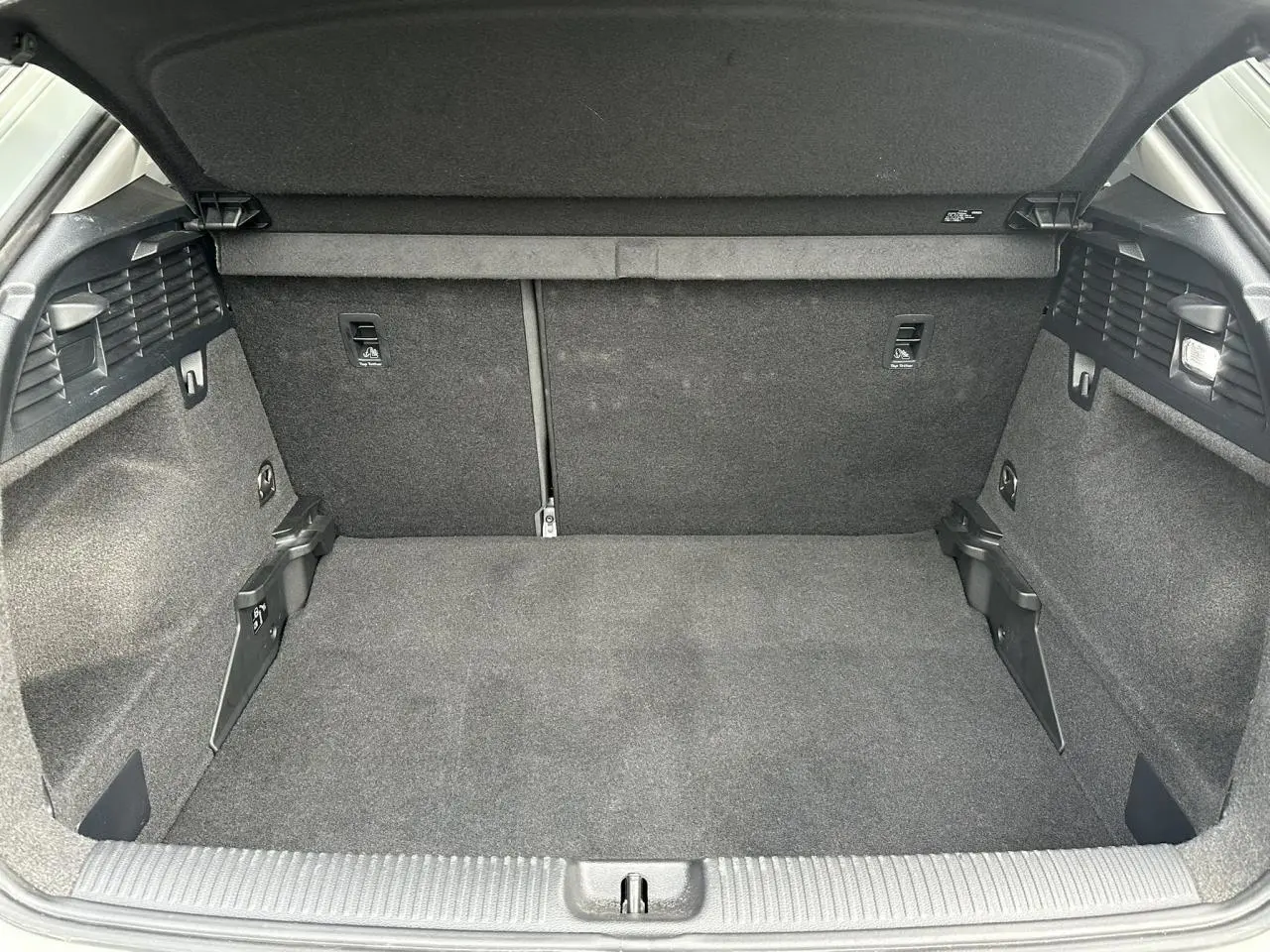 Vue intérieure du coffre spacieux et vide de l'Audi Q2 30 TFSI 110 S-Line 2024, avec revêtement gris foncé.