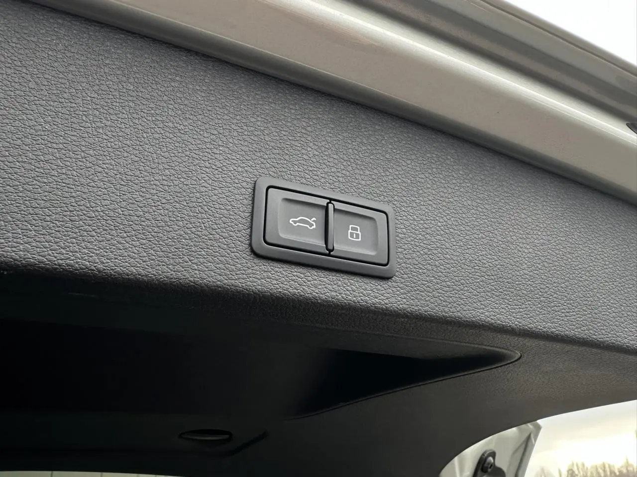 Gros plan sur les boutons d'ouverture et de verrouillage du hayon électrique de l'Audi Q2 argent rosé.