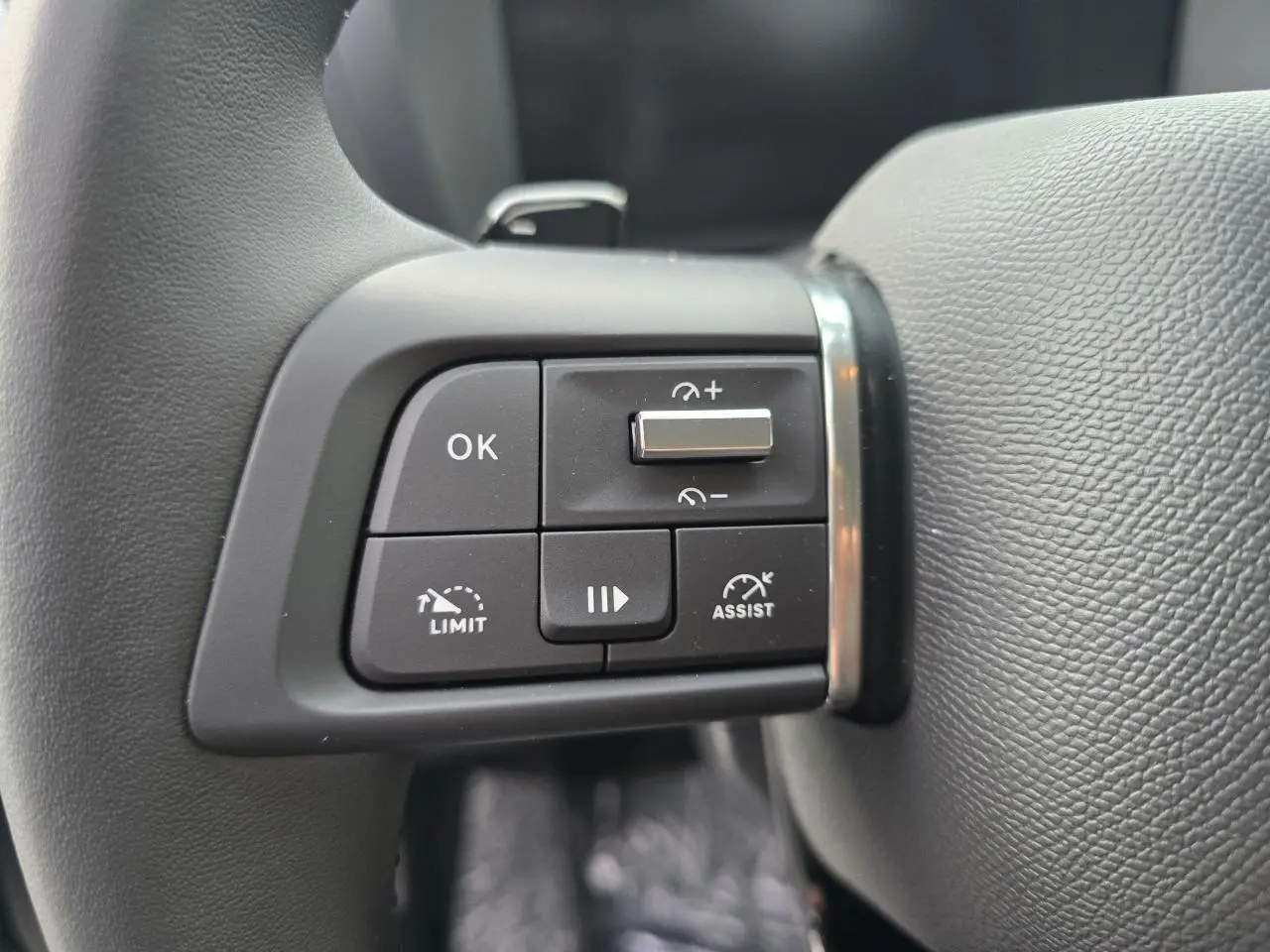 Gros plan sur les commandes de régulateur de vitesse au volant cuir noir du Citroën C4 hybride 2025.