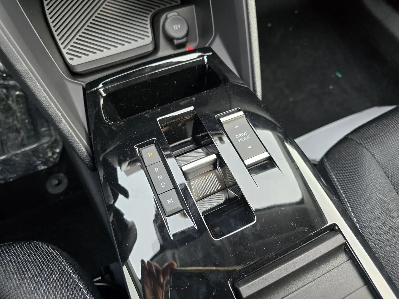 Gros plan sur la console centrale noire brillante avec commandes de boîte auto et mode de conduite de la Citroën C4 hybride.