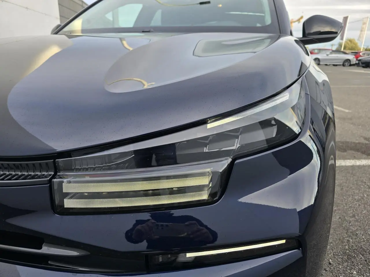 Gros plan sur le phare avant gauche de la Citroën C4 III bleu Éclipse avec toit noir, soulignant son design LED moderne.