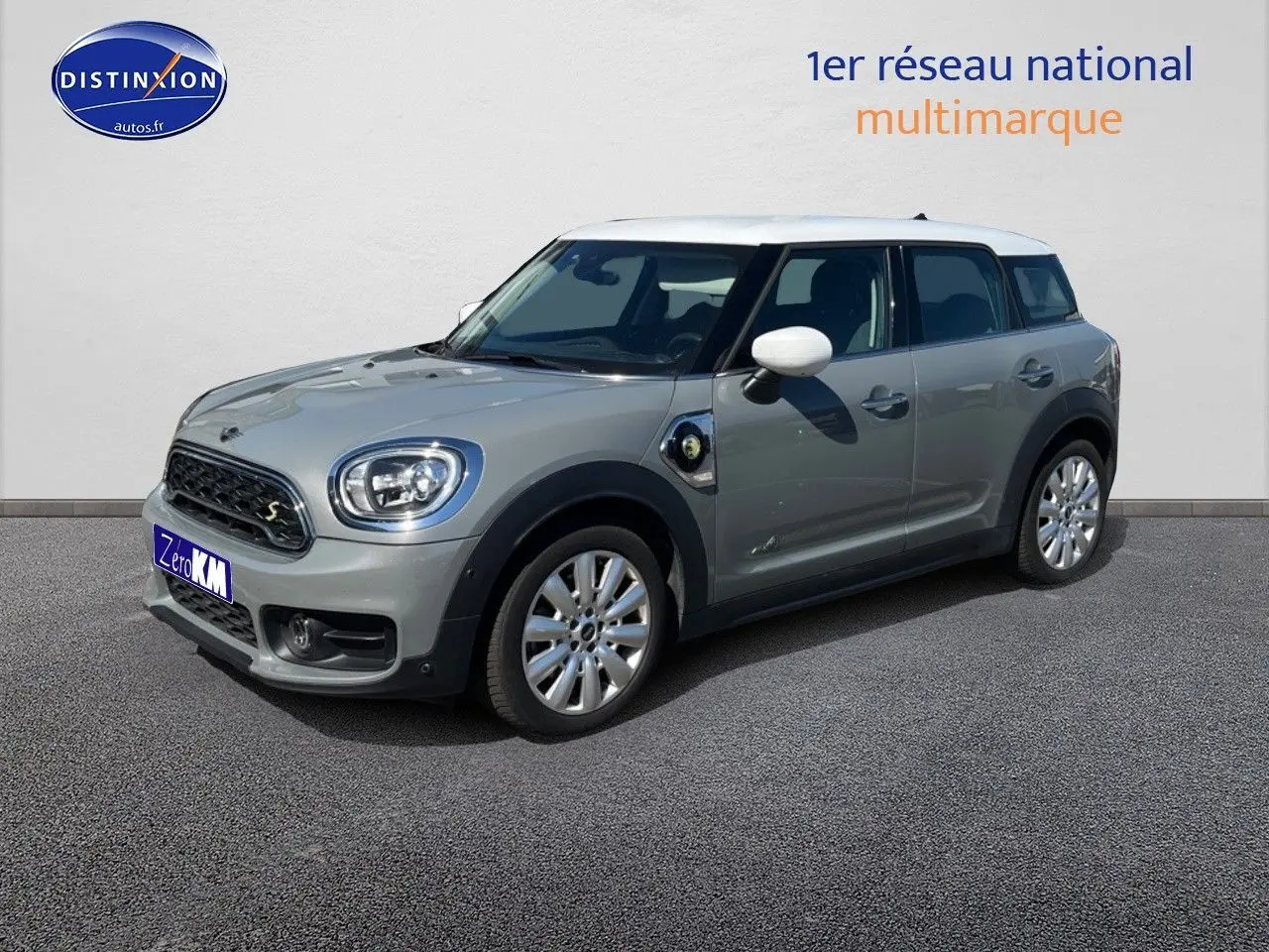 Vue 3/4 avant droite d'une MINI Countryman Cooper SE hybride rechargeable en Moonwalk Grey avec toit blanc et jantes alu design Pin Spoke.