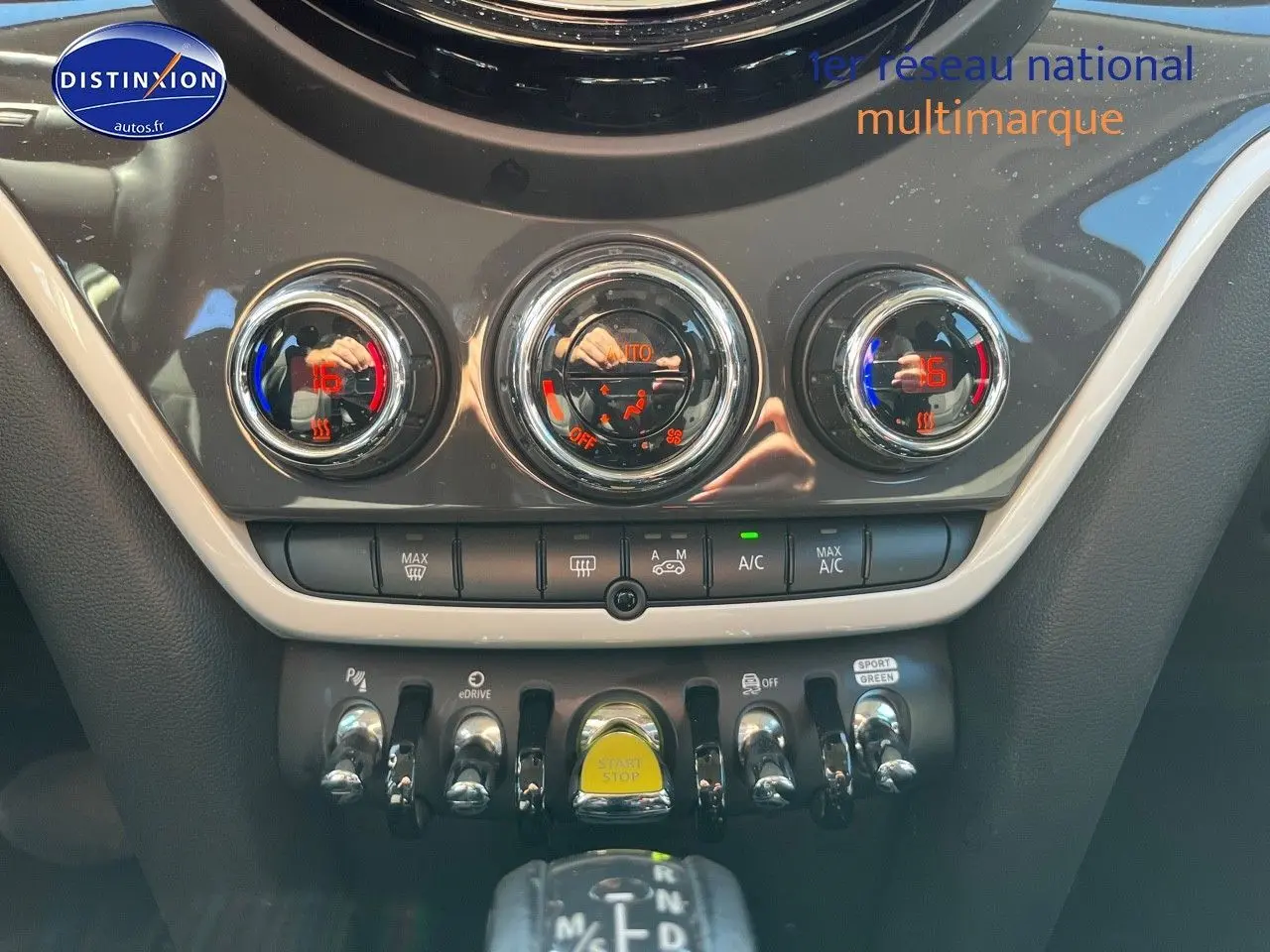 Vue rapprochée de la console centrale du MINI Countryman Moonwalk Grey, avec commandes de climatisation et bouton start/stop jaune.