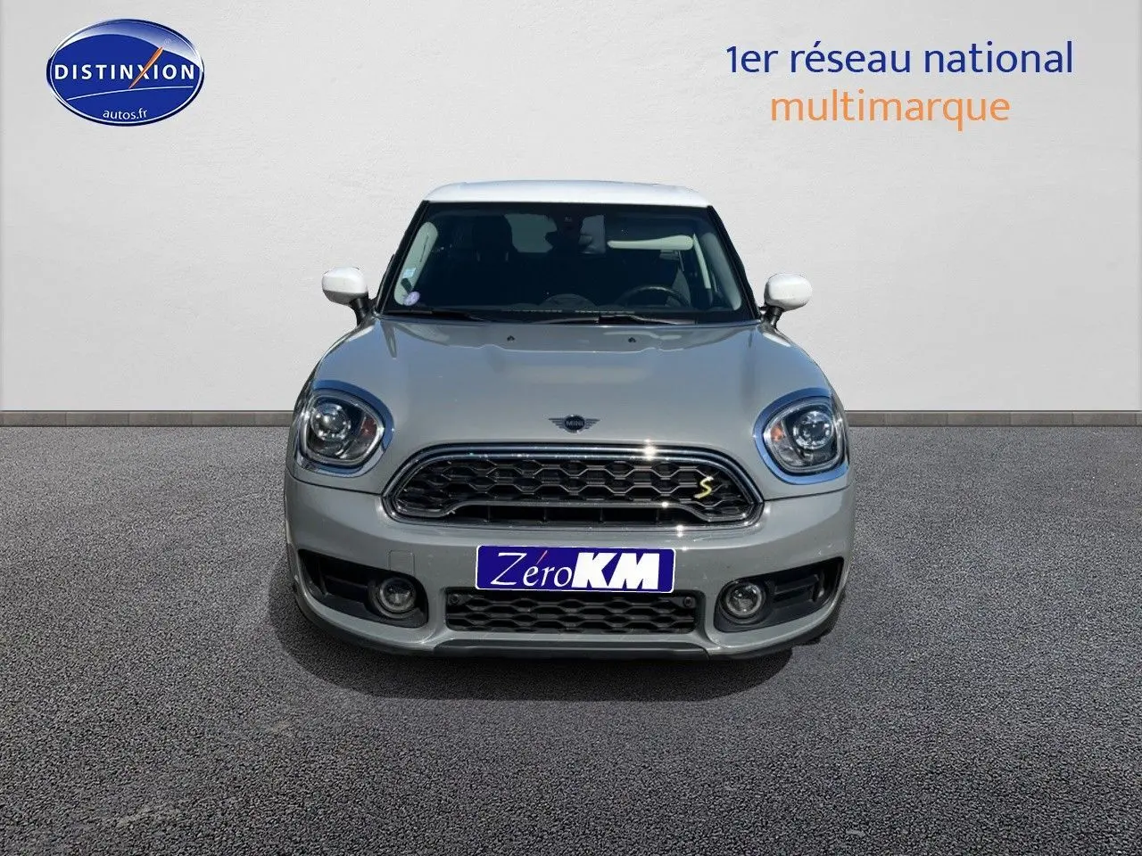 Vue avant d'une MINI Countryman Cooper SE Moonwalk Grey avec toit et rétroviseurs blancs, calandre chromée.