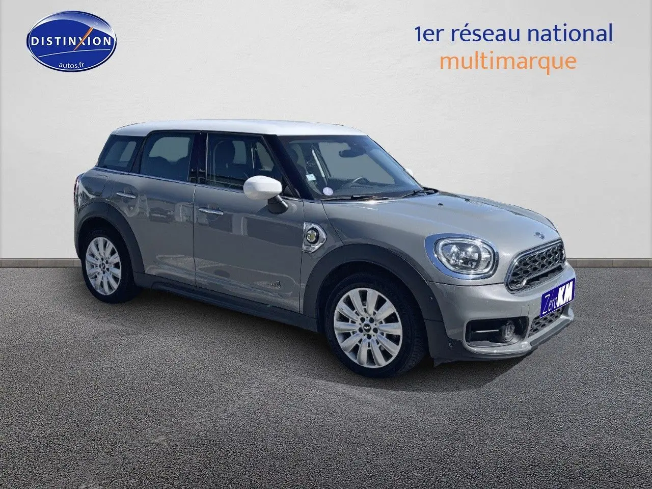 Vue 3/4 avant droit d'une MINI Countryman hybride rechargeable Moonwalk Grey avec toit et rétroviseurs blancs.