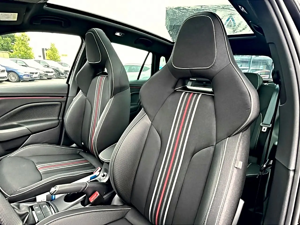 Vue intérieure sur les sièges avant sport noirs avec surpiqûres blanches et bandes rouges du Skoda Kamiq Monte Carlo 2026.