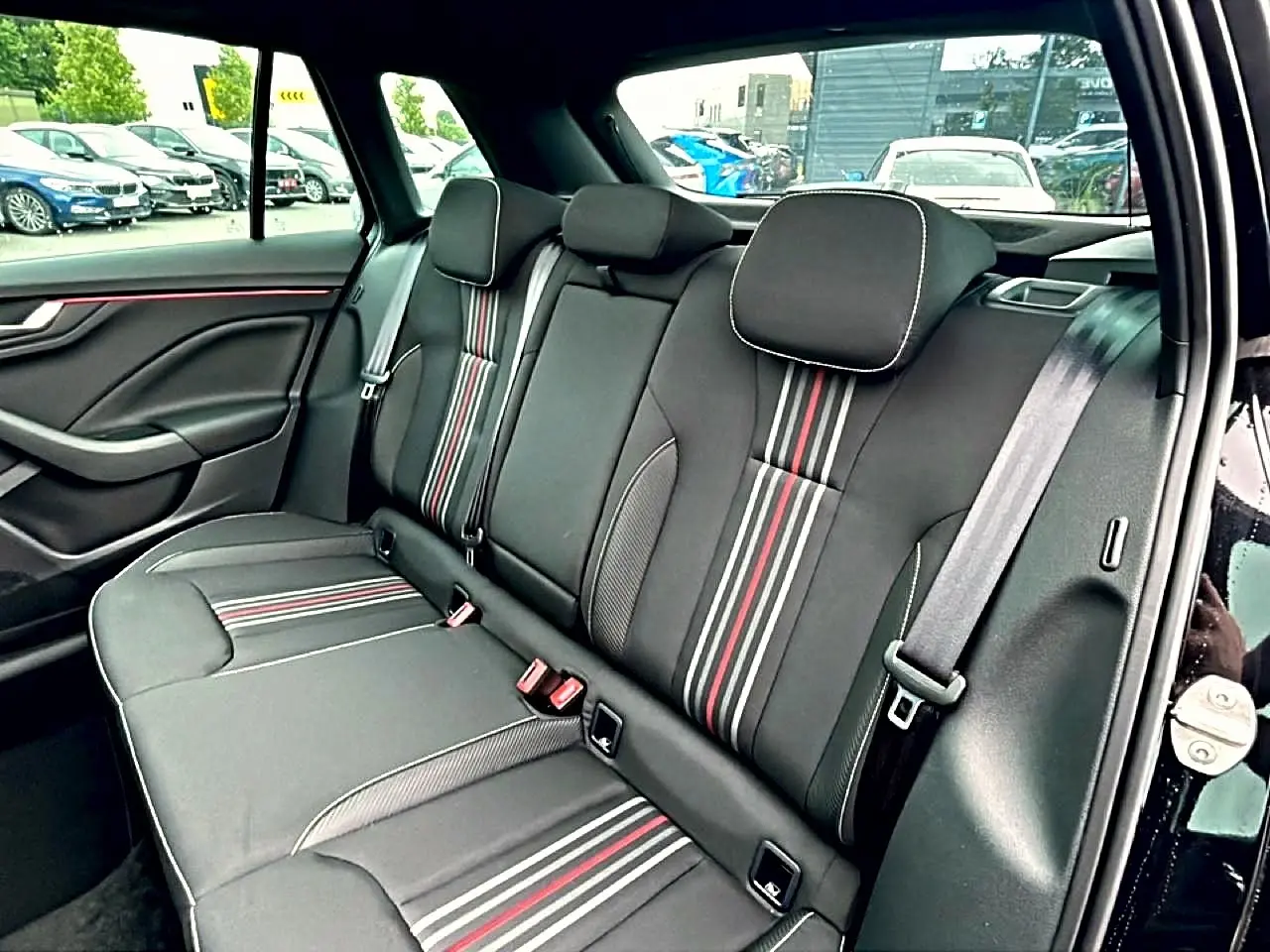 Vue intérieure côté gauche de la banquette arrière noire avec surpiqûres rouges et blanches du Skoda Kamiq Monte Carlo 2026.