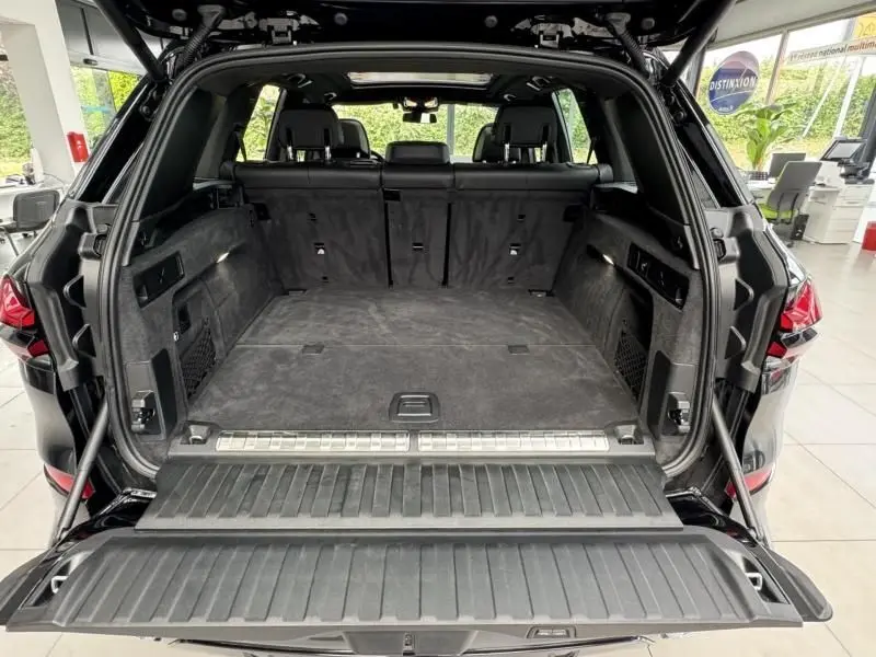 Coffre ouvert vu de l'arrière d'un BMW X5 xDrive50e noir, montrant un grand espace de chargement et banquette arrière.