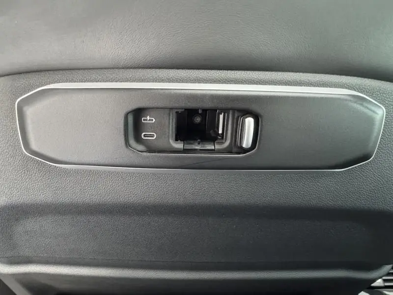 Gros plan sur la commande électrique d'ouverture du coffre noir du BMW X5 xDrive50e 2023, avec prise USB intégrée.