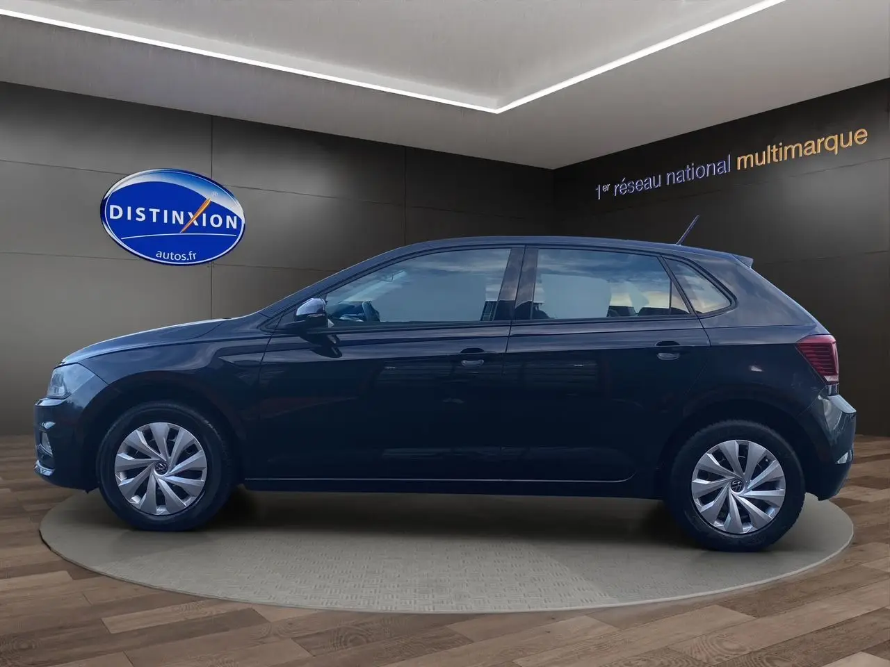 Volkswagen Polo noire intense vue de profil côté gauche dans un showroom avec jantes argentées et cinq portes visibles.