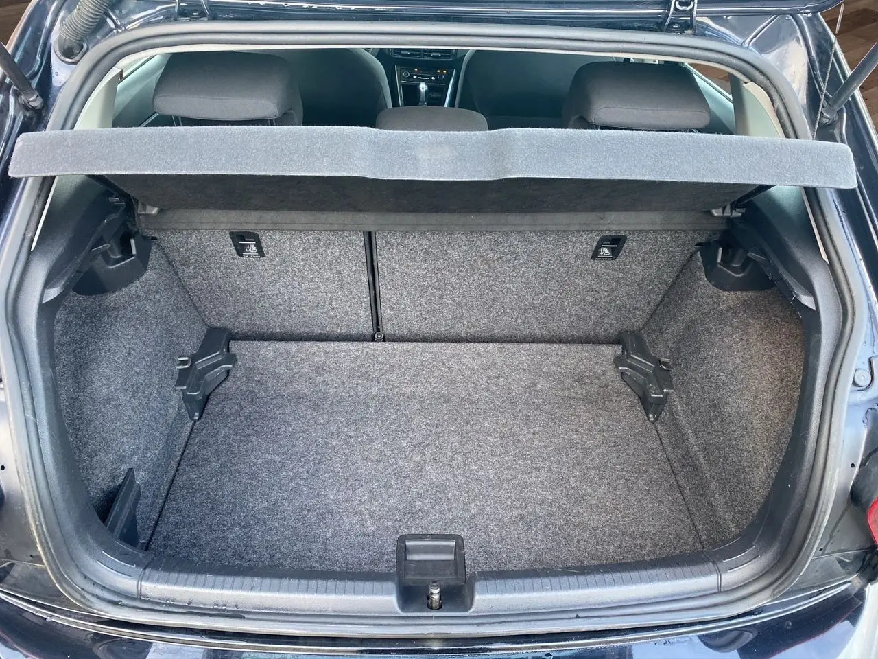 Coffre ouvert vu de l'arrière d'une Volkswagen Polo noire intense 2019, intérieur du coffre en tissu gris.