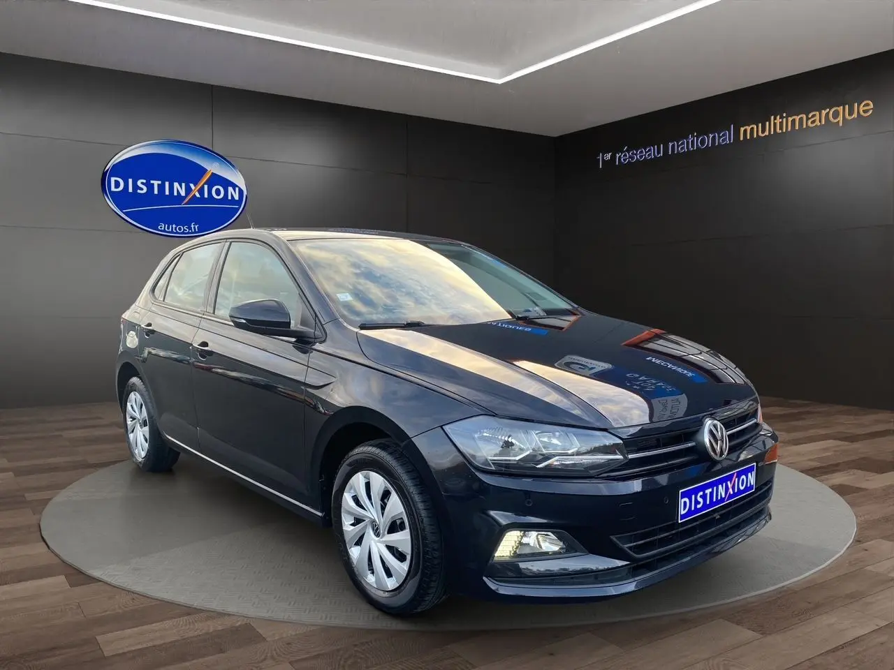 Volkswagen Polo noire vue en 3/4 avant droit, avec phares LED et jantes alliage dans un showroom.