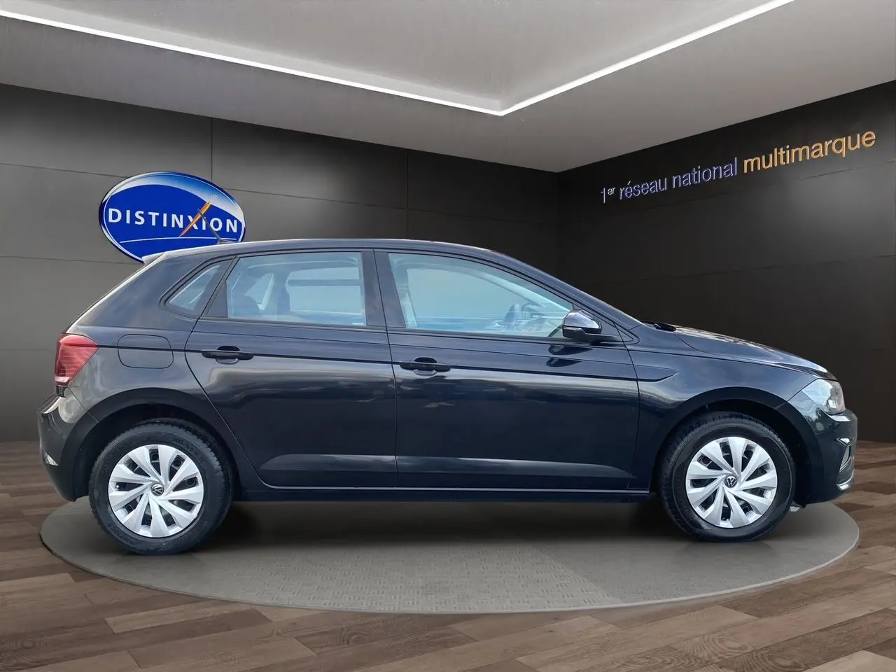 Profil côté gauche d'une Volkswagen Polo noire intense 2019, version 5 portes, sur fond intérieur showroom.