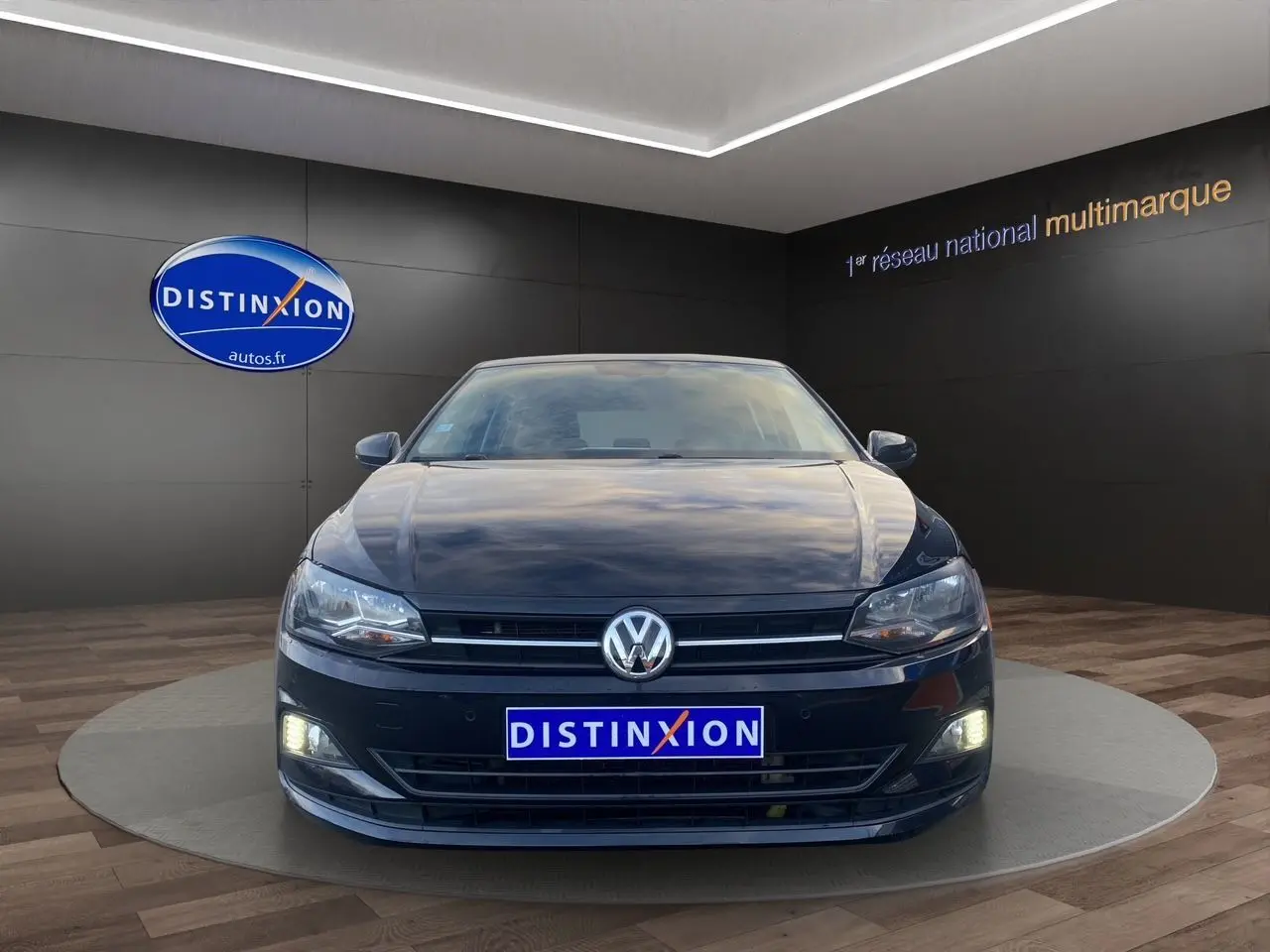 Volkswagen Polo noir intense 2019 vue de face avec phares et feux de jour allumés en showroom.