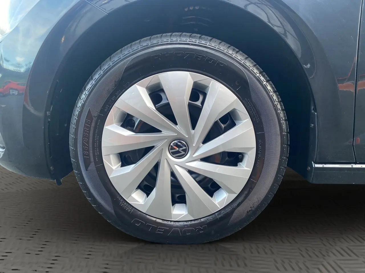 Gros plan sur la roue avant gauche noire intense d'une Volkswagen Polo 2019 avec jante argentée au design moderne.