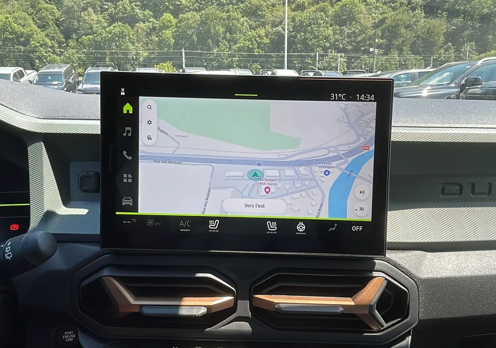 Vue intérieure du tableau de bord du Dacia Duster 2025 blanc, avec écran tactile affichant la navigation GPS.