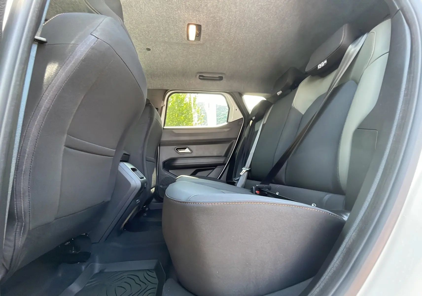 Vue intérieure arrière côté droit du Dacia Duster blanc 2025, montrant les sièges en cuir noir et gris avec ceinture de sécurité.