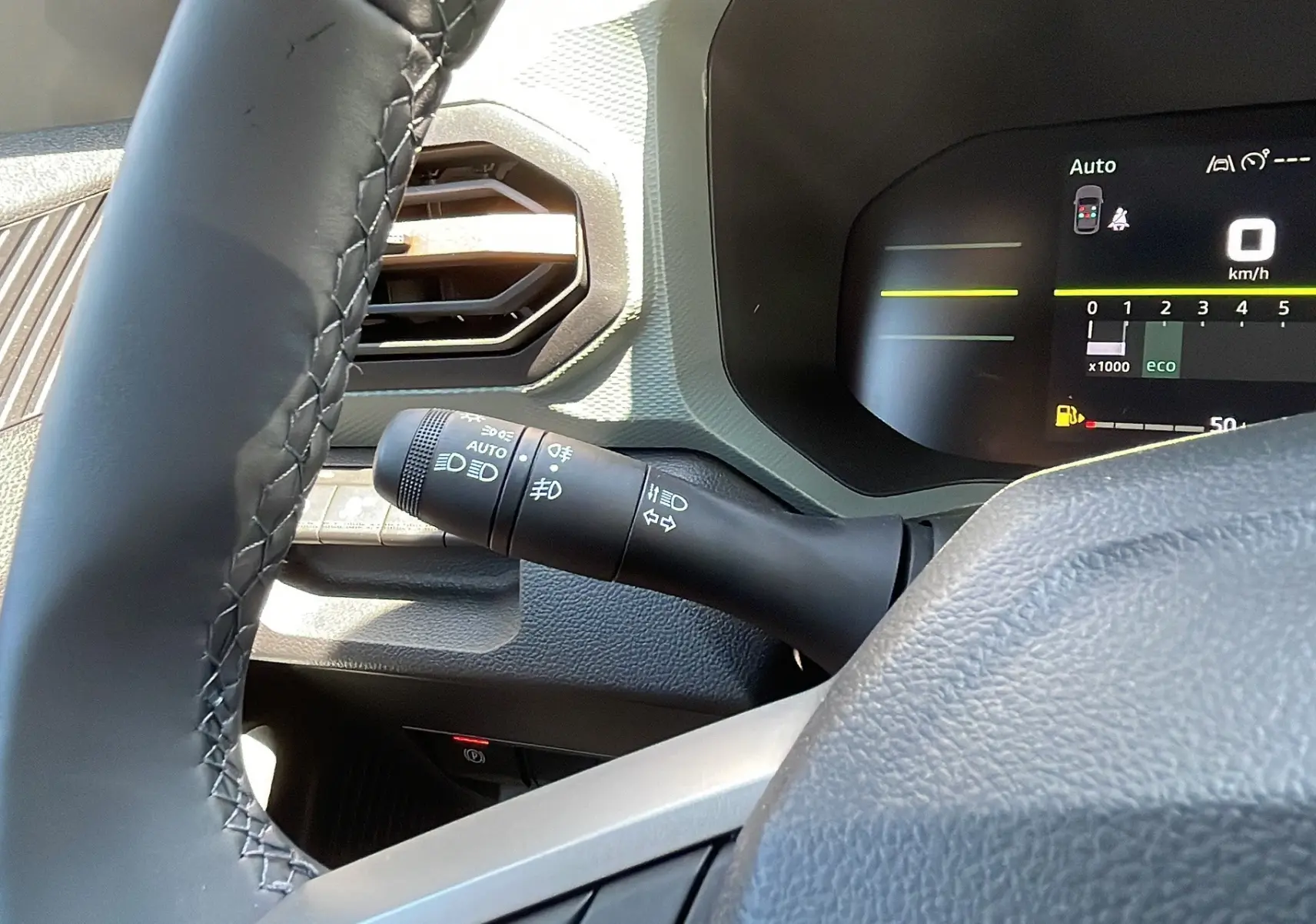 Détail du commodo d'éclairage à gauche du volant dans le tableau de bord du Dacia Duster blanc 2025, version Extreme Plus.