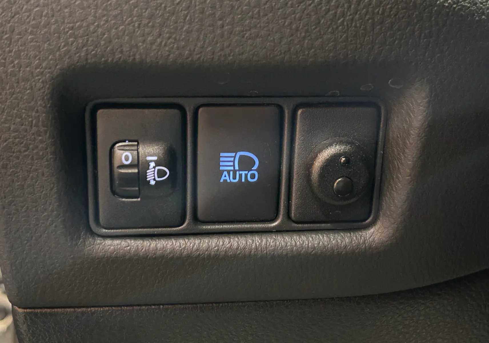 Panneau de commandes des phares avec réglage manuel et mode automatique, intérieur noir du Toyota C-HR Hybride 2021.