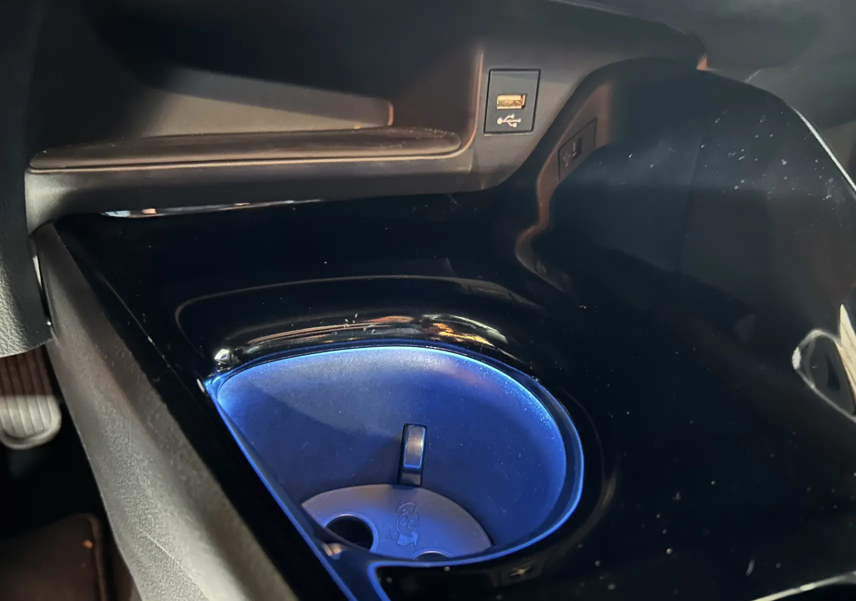 Gros plan sur le porte-gobelet éclairé en bleu dans l'habitacle noir du Toyota C-HR Hybride 2021.