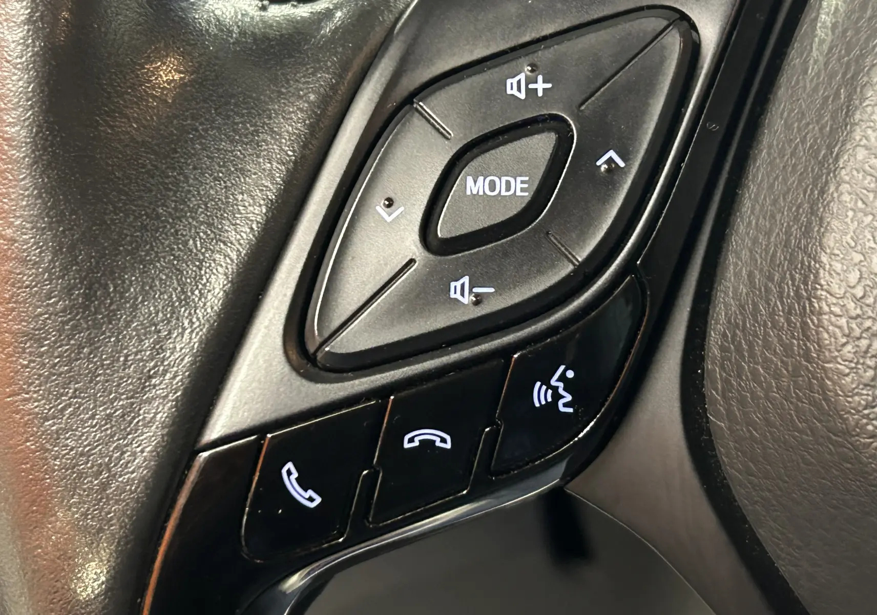 Gros plan sur les commandes au volant noir du Toyota C-HR Hybride 122h Edition 2WD 2021, boutons audio et téléphone.