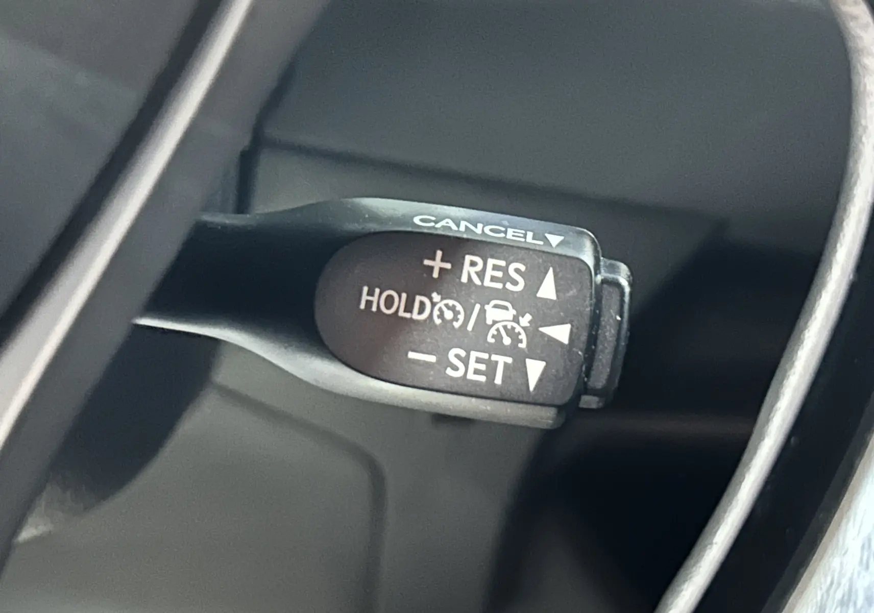 Gros plan sur le levier de régulateur de vitesse du Toyota C-HR Hybride noir métal, version 2021, intérieur côté gauche.