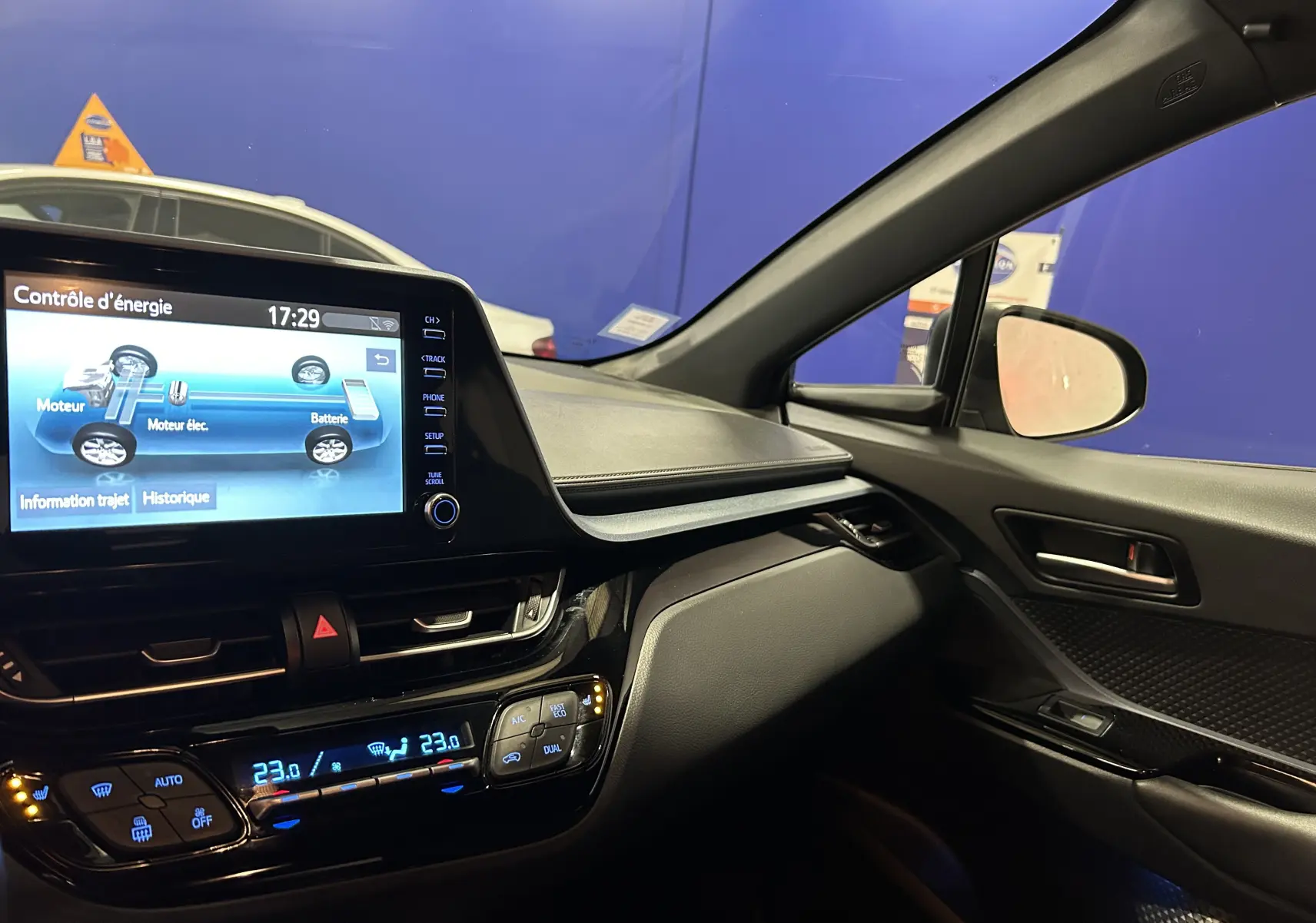 Intérieur du Toyota C-HR Hybride 2021 vu côté passager, avec écran tactile affichant le contrôle d'énergie et climatisation digitale.