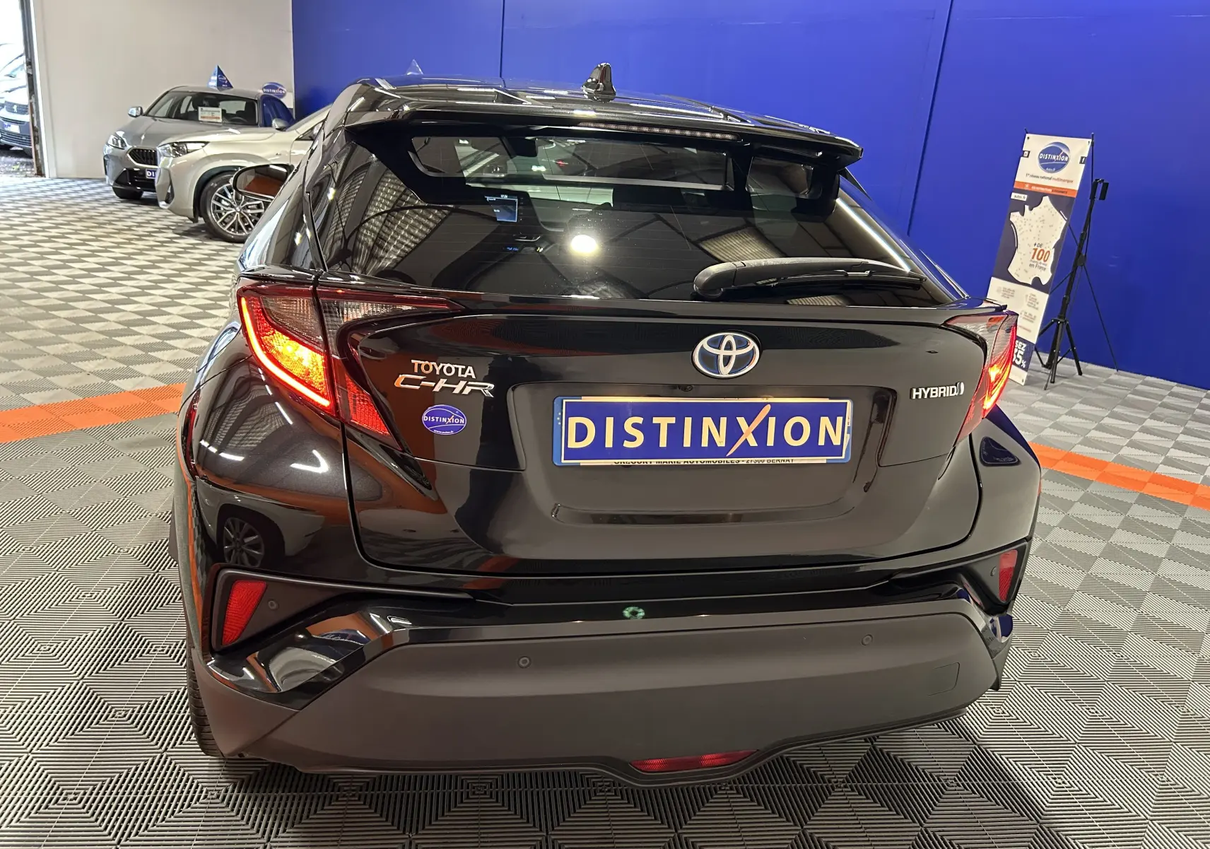 Vue arrière d'un Toyota C-HR Hybride noir métal 2021 avec feux allumés dans un showroom intérieur.