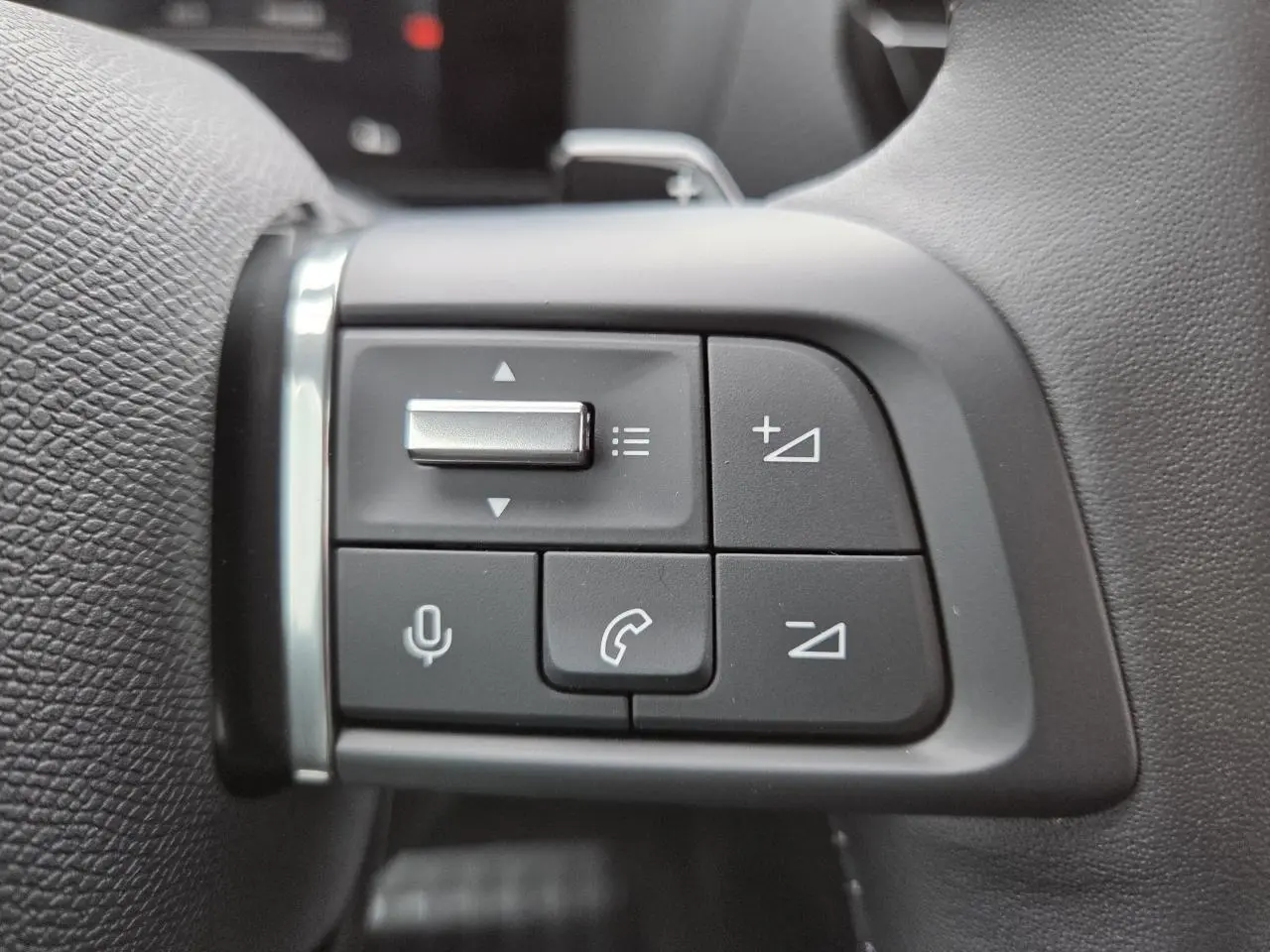 Gros plan sur les commandes au volant du côté gauche du Citroën C4 blanc Okenite, version hybride 2025.