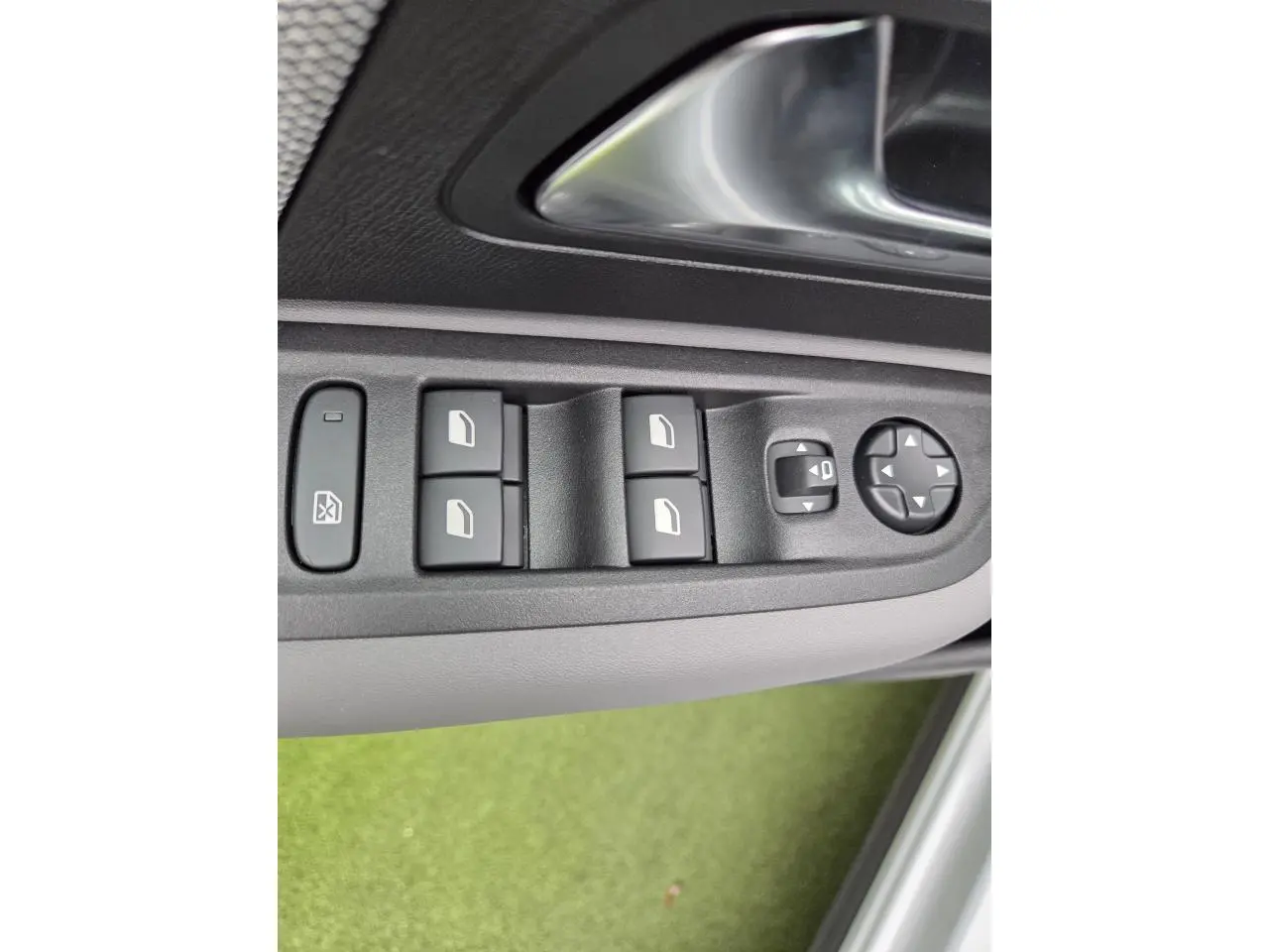 Gros plan sur les commandes de lève-vitres et réglages des rétroviseurs côté conducteur d'une Citroën C4 blanche.