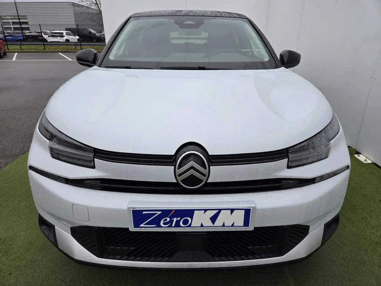 Vue avant d'une Citroën C4 blanche Okenite avec toit noir et logo double chevron bien visible.