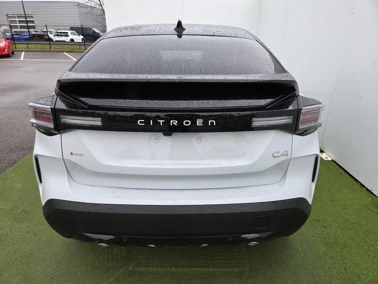 Vue arrière d'une Citroën C4 blanche avec toit noir et feux arrière LED distinctifs sous la pluie.