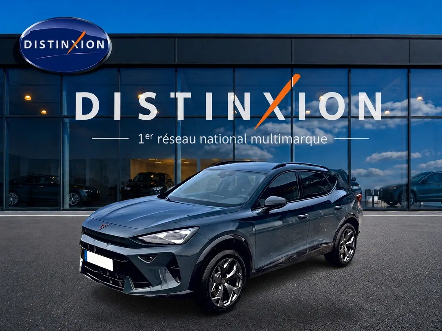 Vue 3/4 avant droit d'un CUPRA Formentor 1.5 etsi hybrid bleu fjord avec jantes 18 pouces devant un showroom Distinxion.