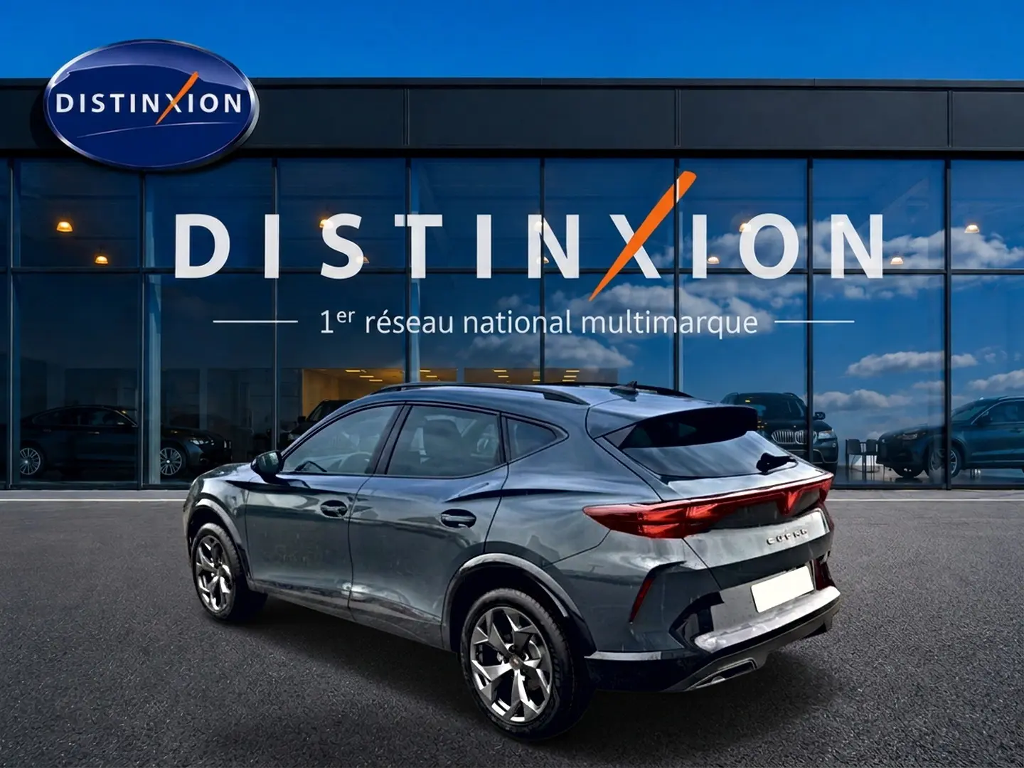 Vue 3/4 arrière d'un CUPRA Formentor bleu fjord 2026 avec feux arrière LED et jantes 18 pouces devant un showroom Distinxion.