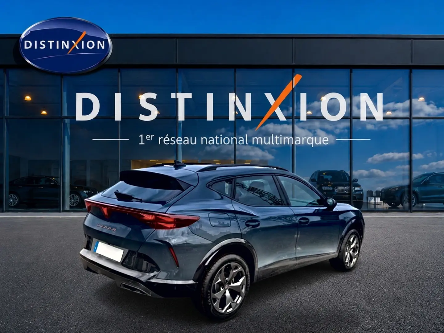 Vue 3/4 arrière droite d'un CUPRA Formentor bleu fjord 2026 avec jantes 18 pouces, garé devant un showroom Distinxion.
