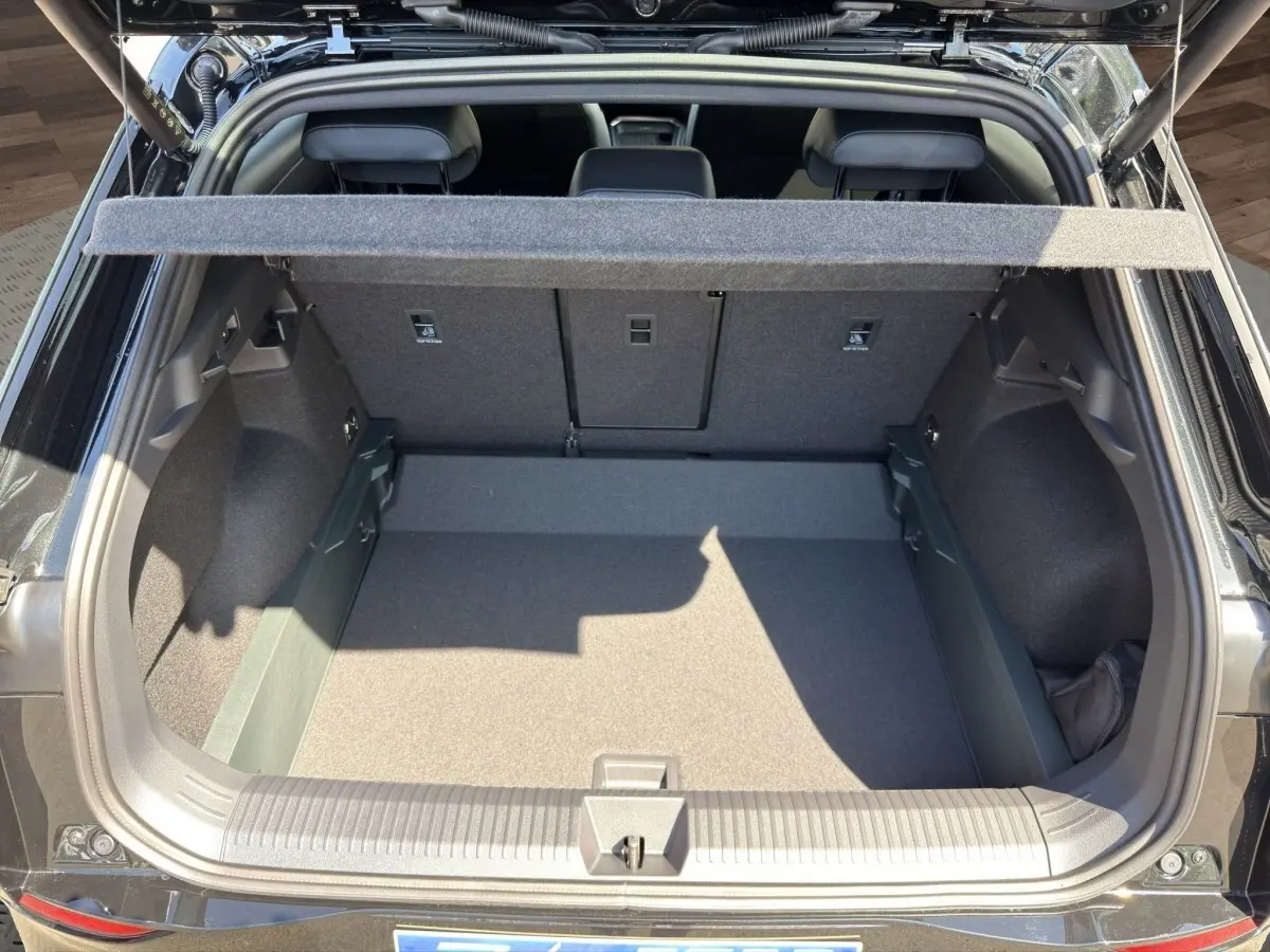 Coffre ouvert vu de l'arrière d'un Volkswagen T-Roc noir, montrant l'espace de chargement et la tablette cache-bagages.