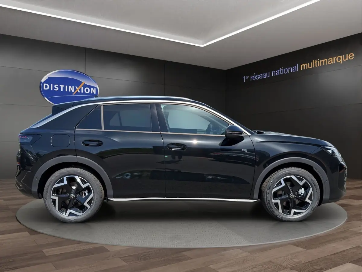 Vue latérale droite du Volkswagen T-Roc noir 2026 avec jantes alliage et toit ouvrant panoramique en showroom.