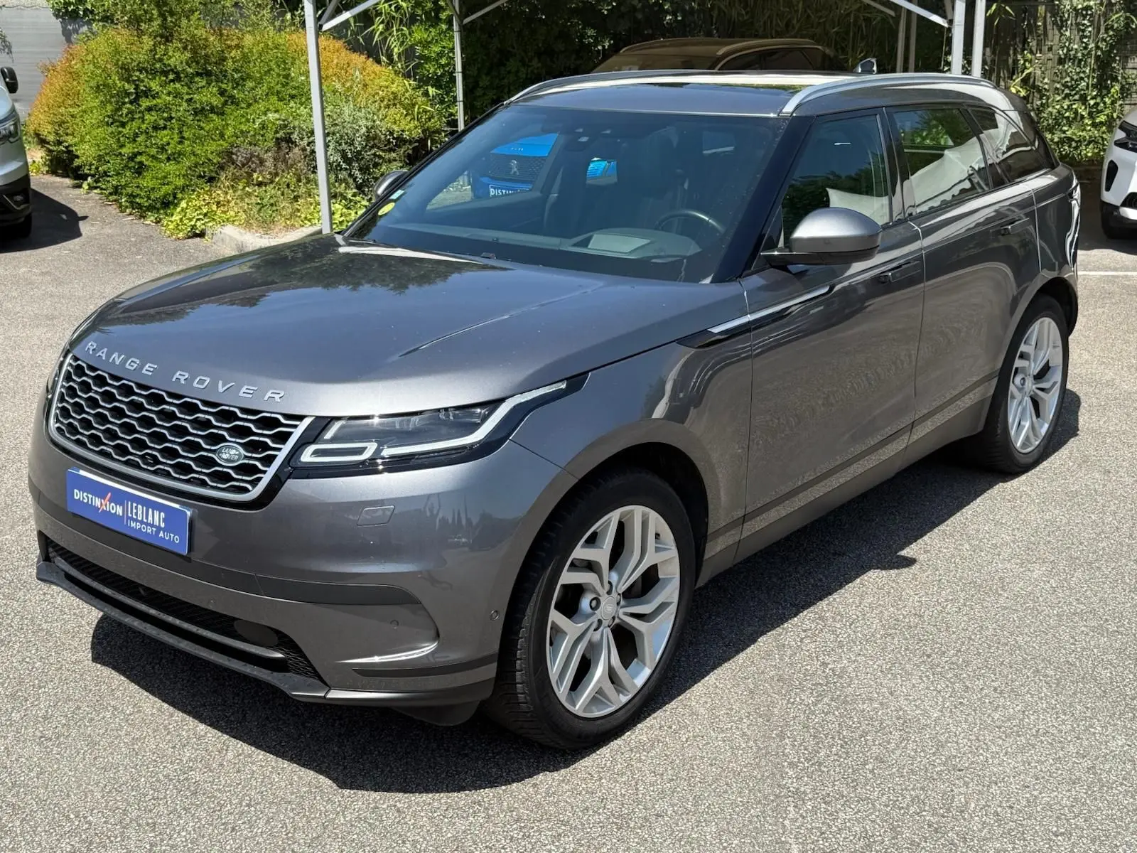 Vue 3/4 avant d'un Range Rover Velar gris métallisé avec calandre distinctive et jantes alliage argentées.