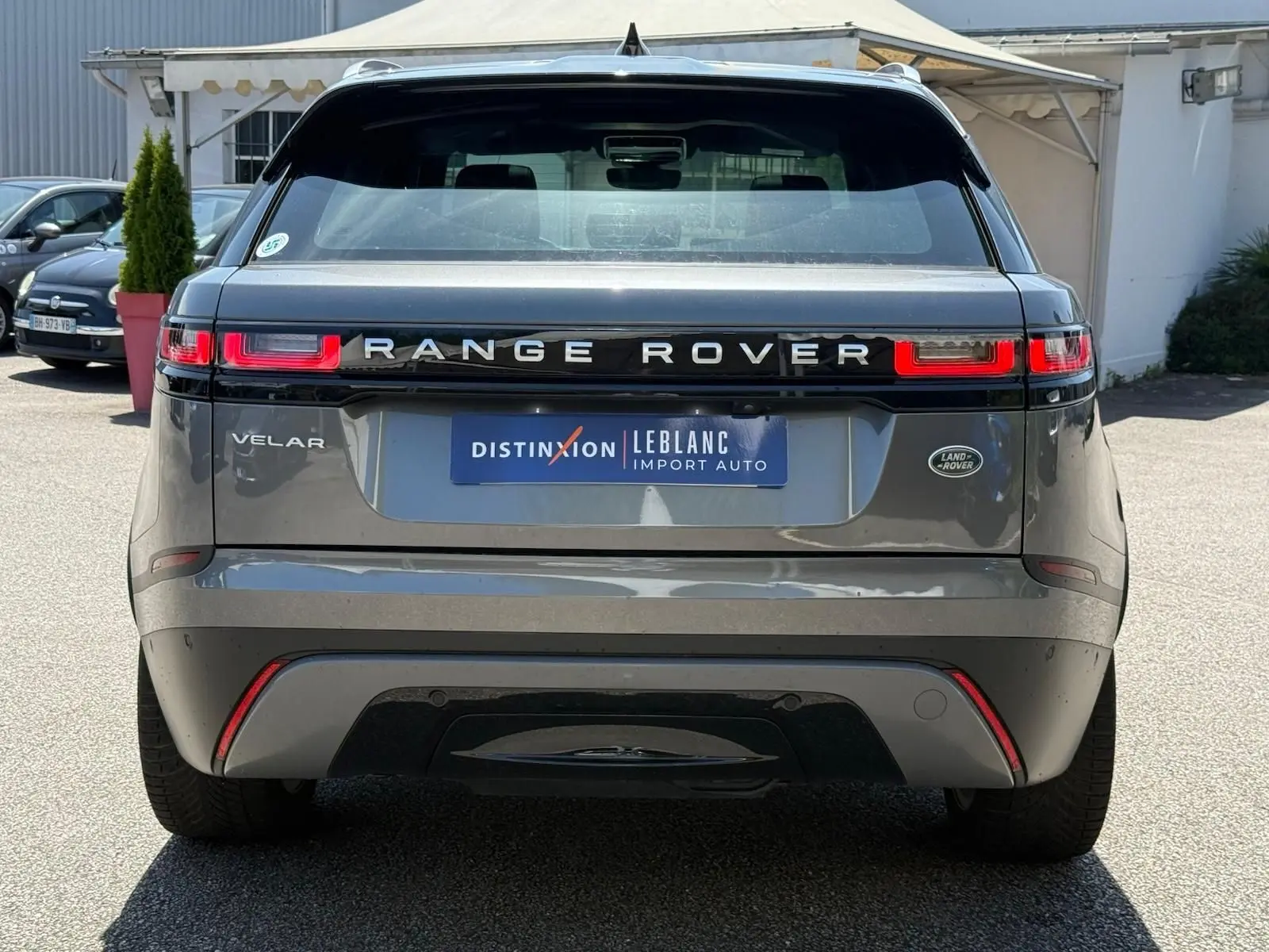 Vue arrière d'un Range Rover Velar gris 2019 avec feux LED distinctifs et logo Land Rover visible.