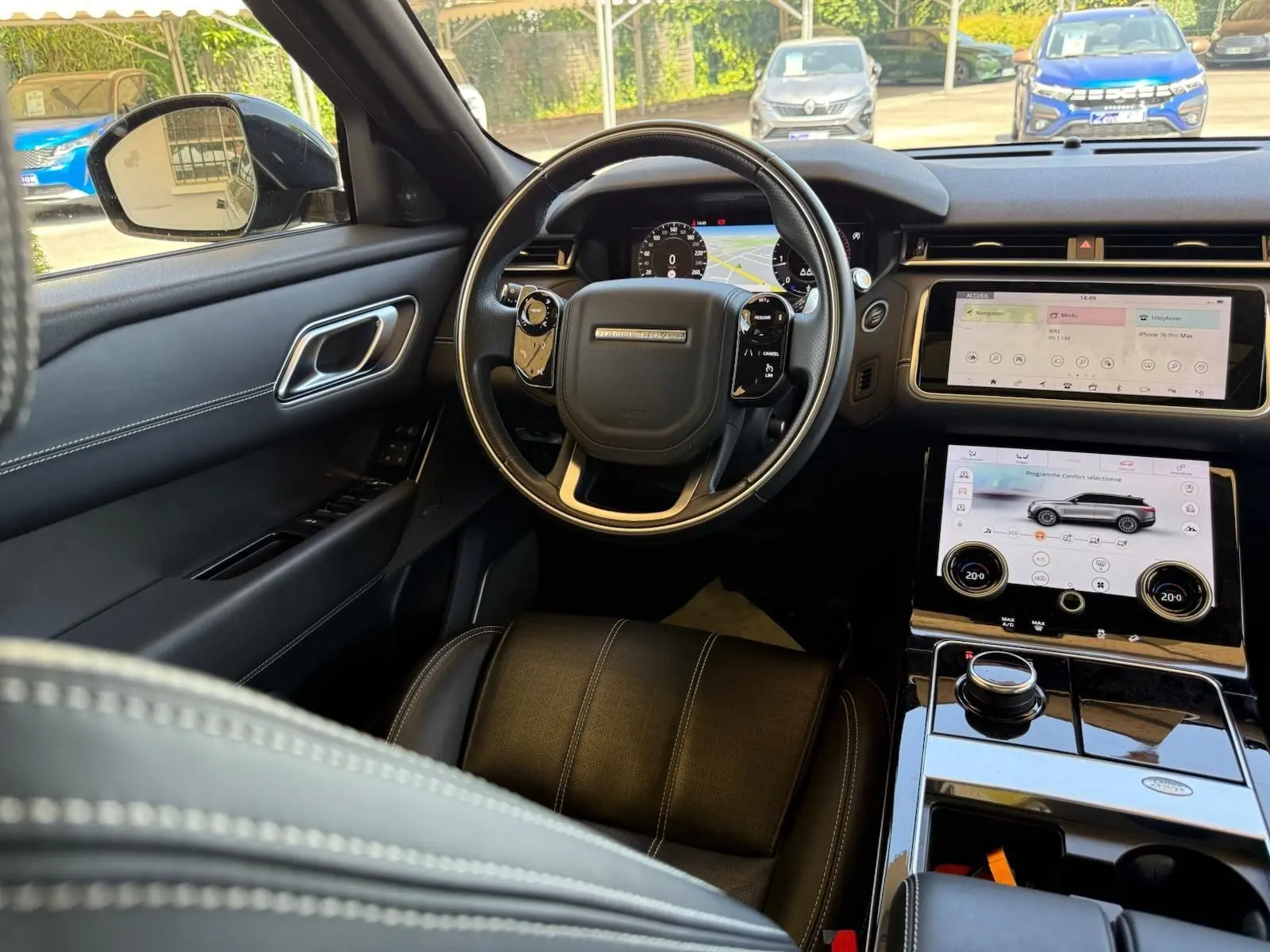 Vue intérieure côté conducteur du Range Rover Velar gris 2019, tableau de bord numérique et écran tactile central visibles.
