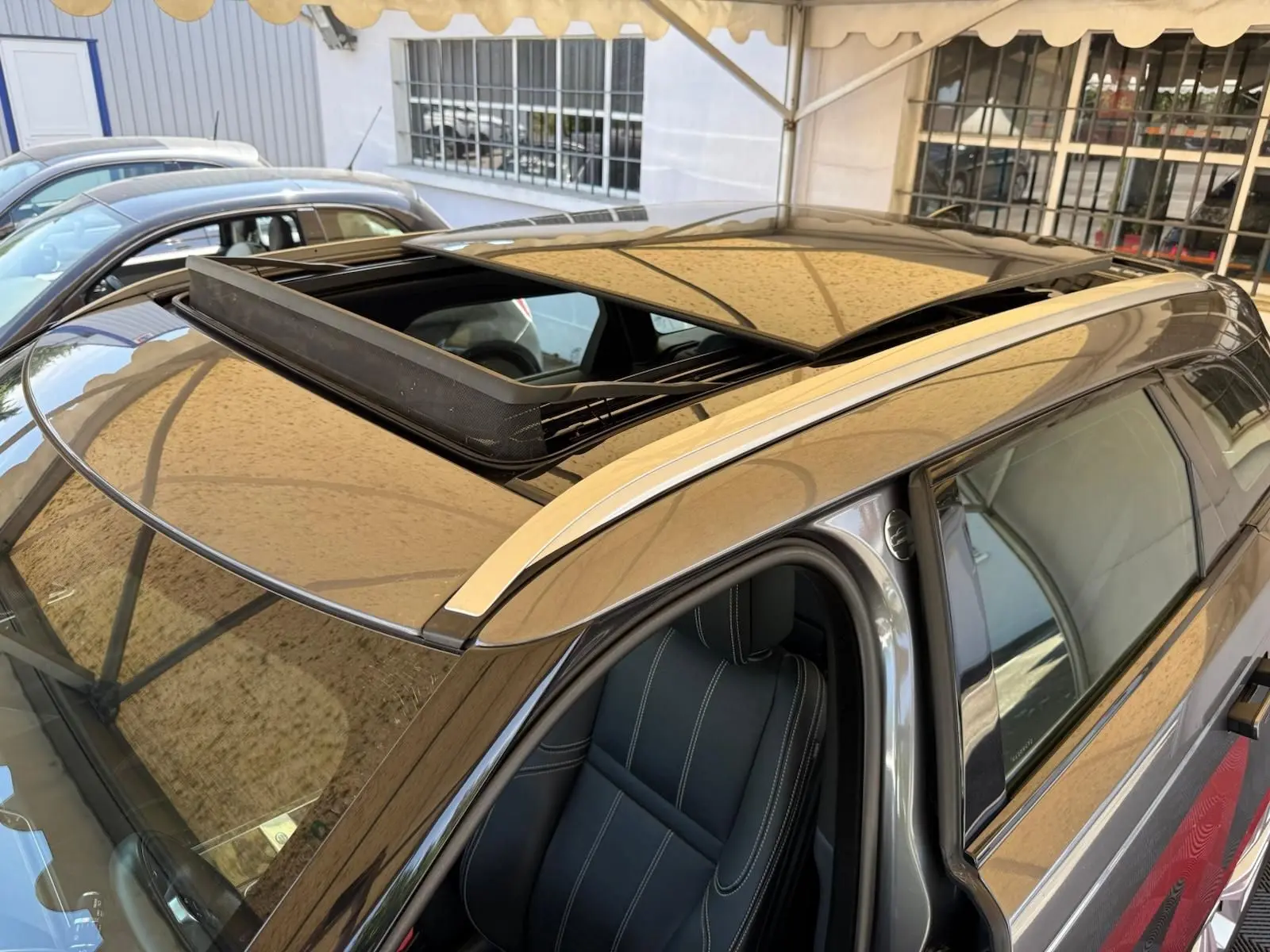 Vue plongeante sur le toit ouvrant et siège avant gauche d'un Range Rover Velar gris métallisé 2019.